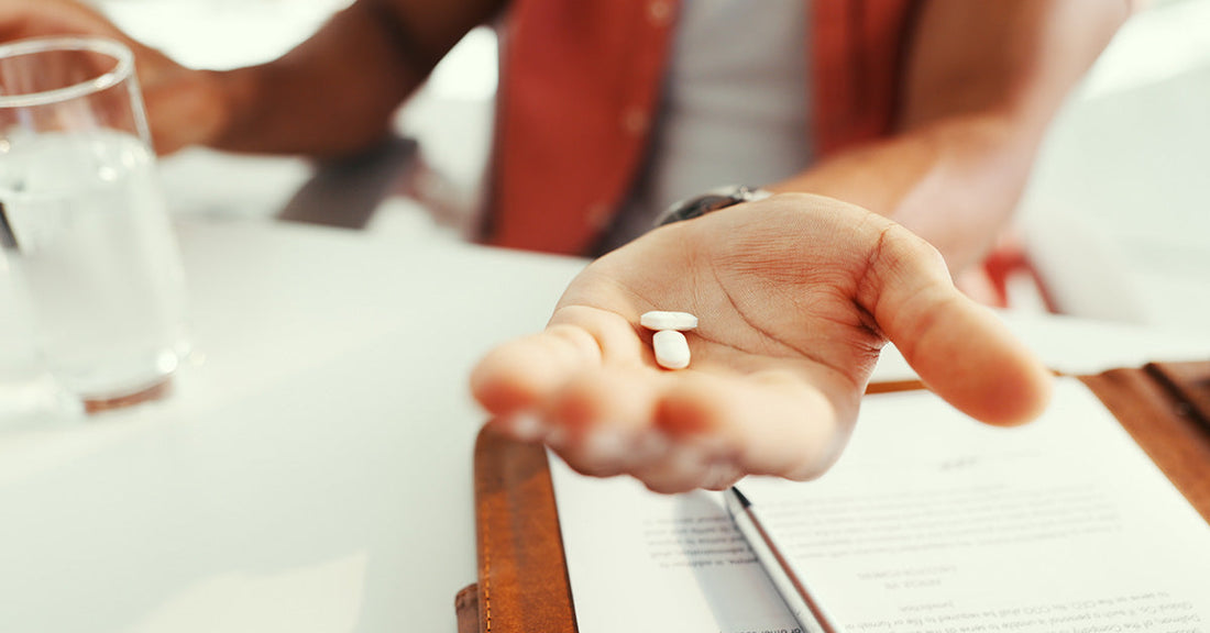 person's hand holding two white pills
