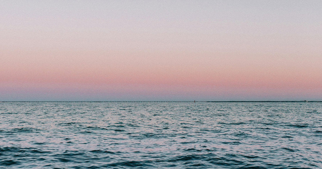 Calm ocean under a pink and blue gradient sky at dusk with the horizon stretching across.
