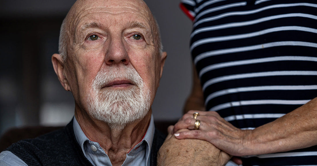 senior man with caregiver in the background