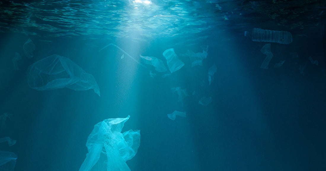 plastic pollution floating underwater with sun beaming through