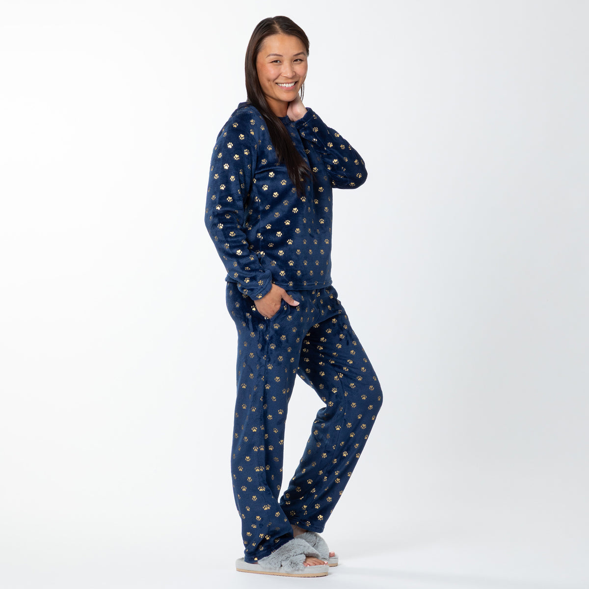 Woman wearing navy blue pajamas with gold paw prints on a white background.
