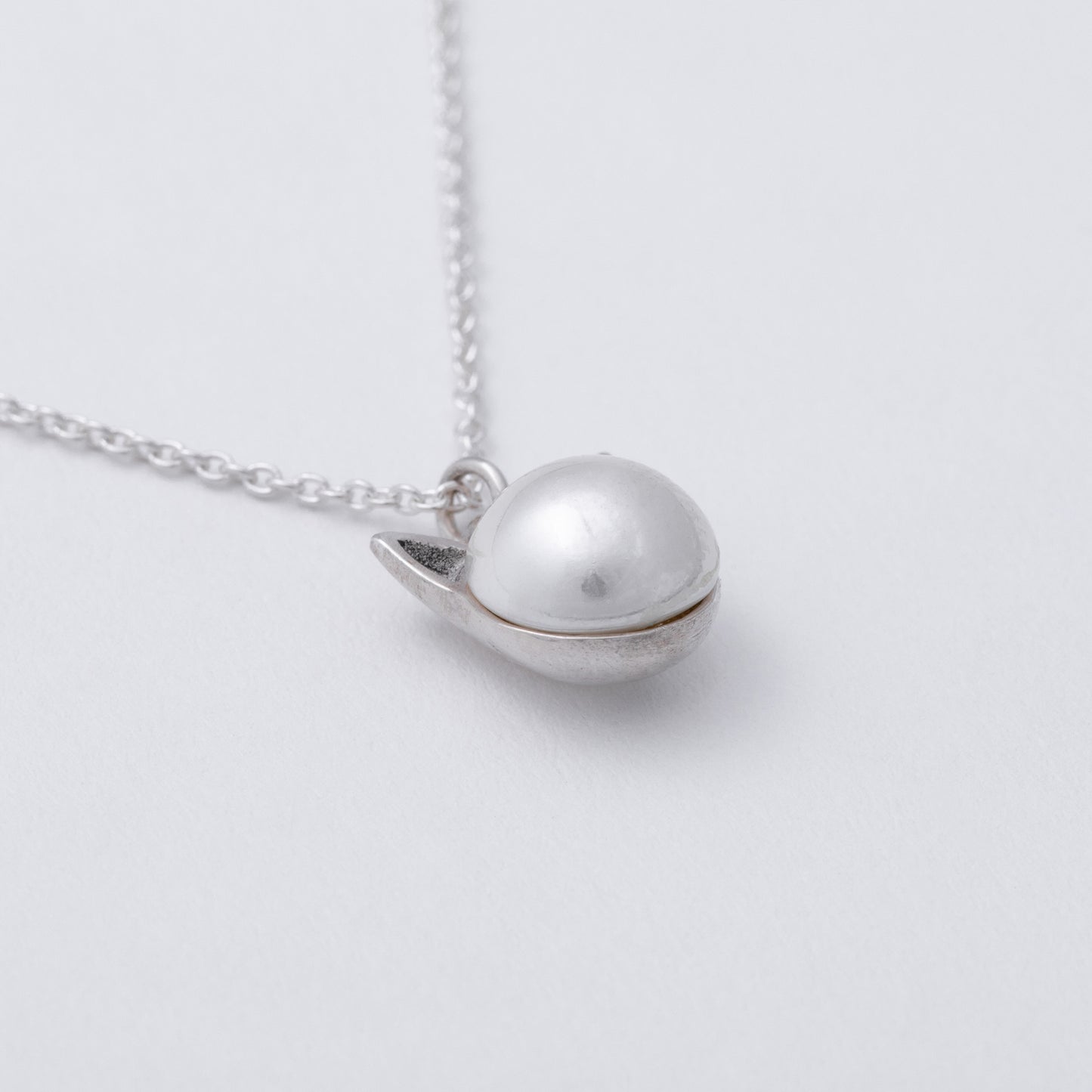 Silver necklace with a unique pendant on a light gray background