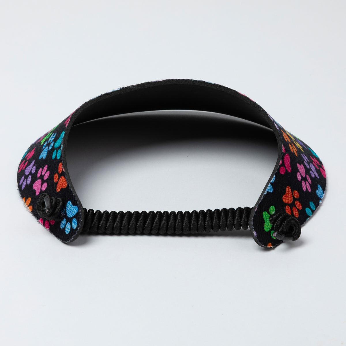 Black visor with colorful paw print design on a light gray background