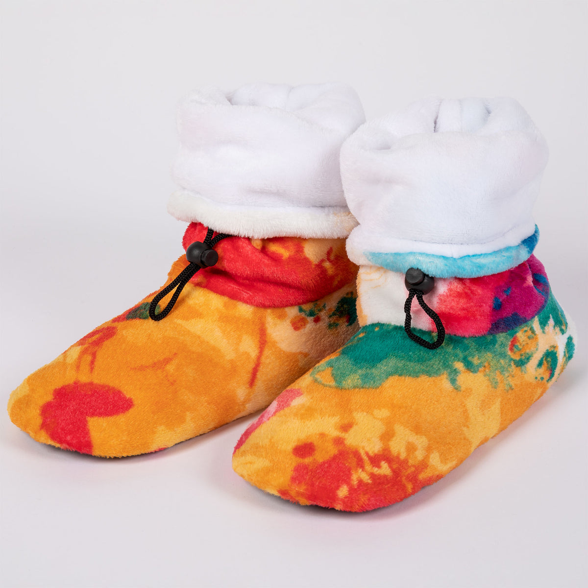 Bright watercolor style fleece slipper booties with abstract paw prints all over, and a white fleece lining, on a white background.
