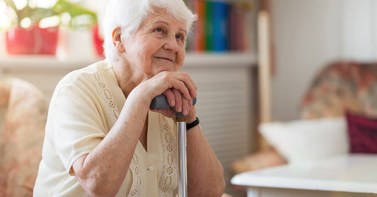 elderly woman resting her head on cane in home setting
