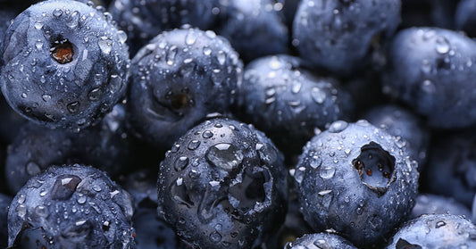 Close-up of ripe blueberries covered in water droplets, highlighting their deep blue color and textured skins.