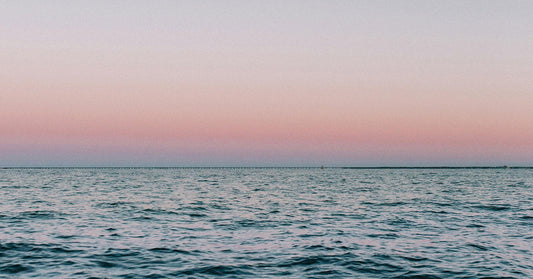 Calm ocean under a pink and blue gradient sky at dusk with the horizon stretching across.