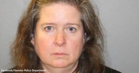 Mugshot of a woman with long brown hair against a gray background.