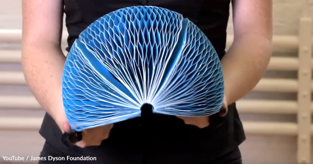 Person holding a blue, fan-shaped paper art piece with a honeycomb texture.