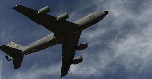 U.S. Air Force aerial refueling aircraft flying overhead against a partly cloudy sky.