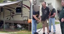 Travel trailer parked behind a fence with clutter around it in a yard. Man in handcuffs being escorted by law enforcement officers outside a home.