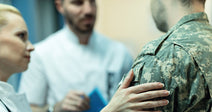 Medical professionals consult with a soldier in a healthcare setting.