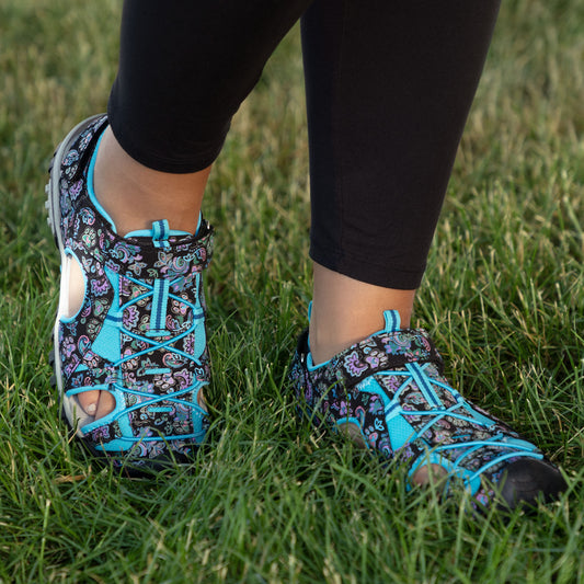 Colorful patterned shoes worn by a person standing on green grass.