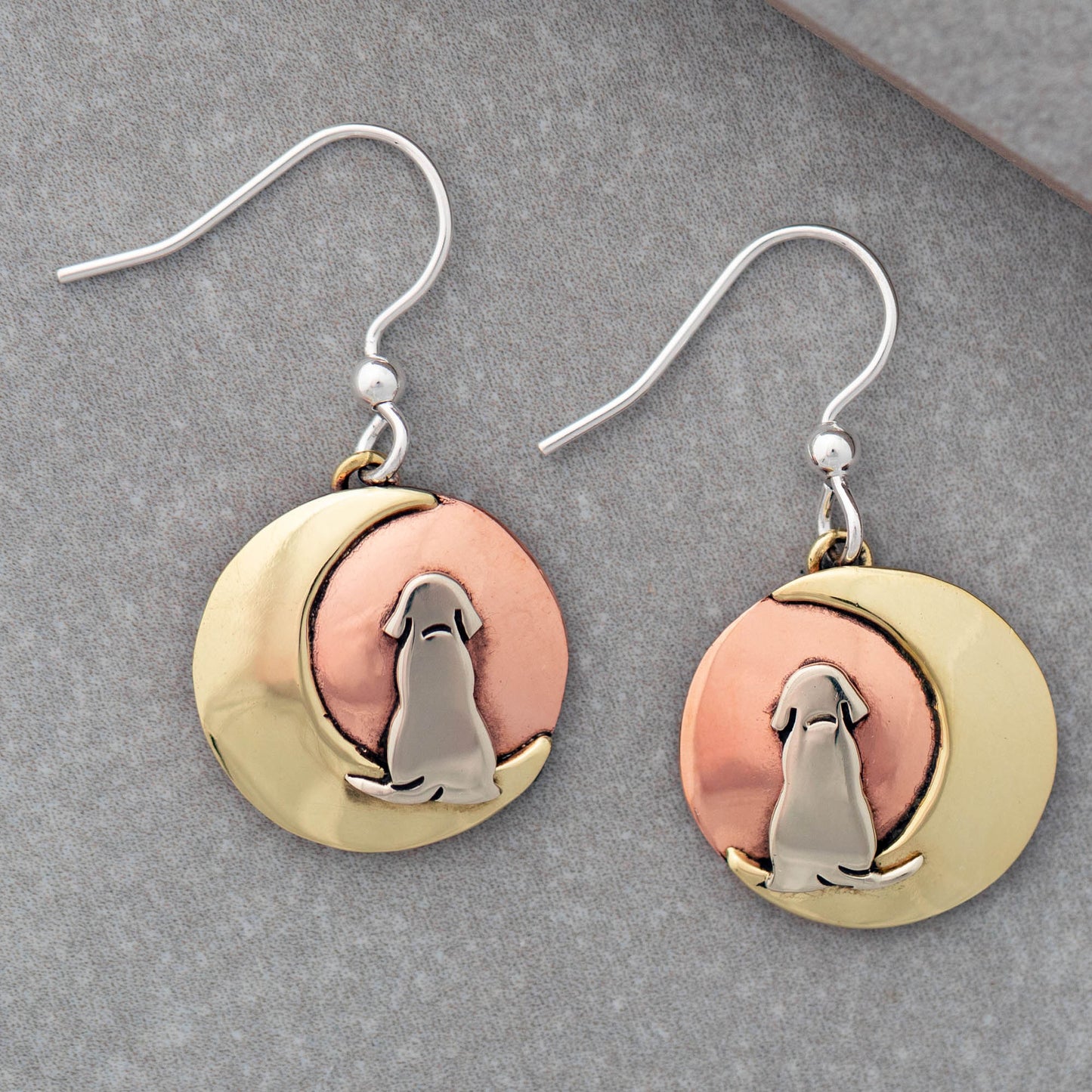 Pair of earrings with a moon, featuring a dog silhouette on a gray surface