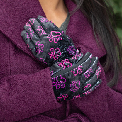 A woman, outside, wearing a coat and a pair of touchscreen technology fingertips warm black fleece gloves adorned with prink and violet elegant paw prints. 