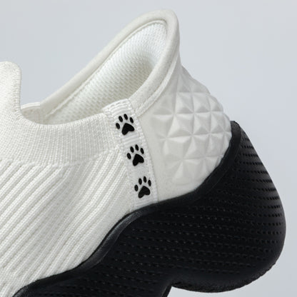 White slip-on shoe with black paw prints on a light gray background