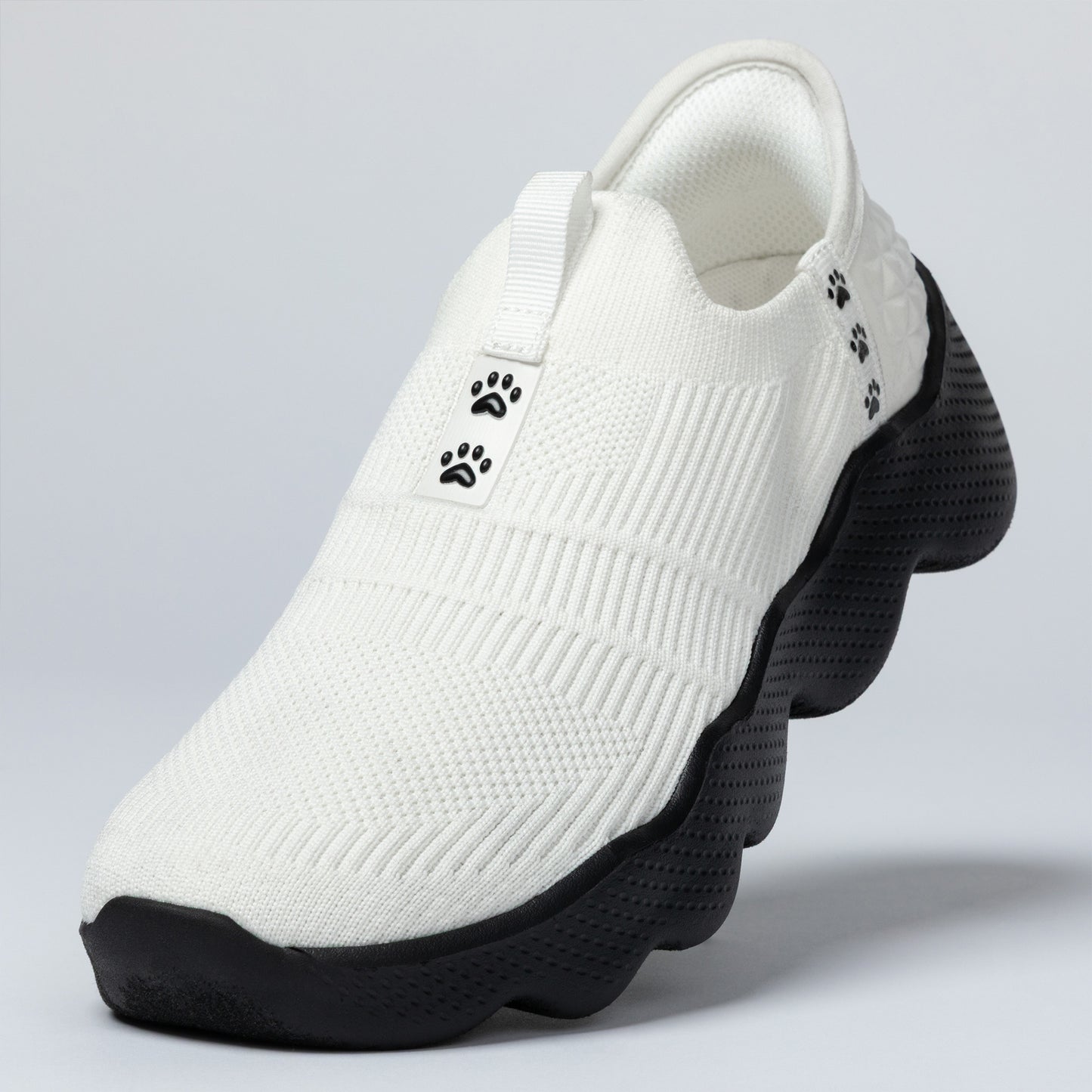 White slip-on shoe with black sole on a light gray background