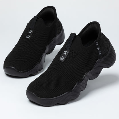 Pair of black slip-on shoes with paw print accents on a light gray background