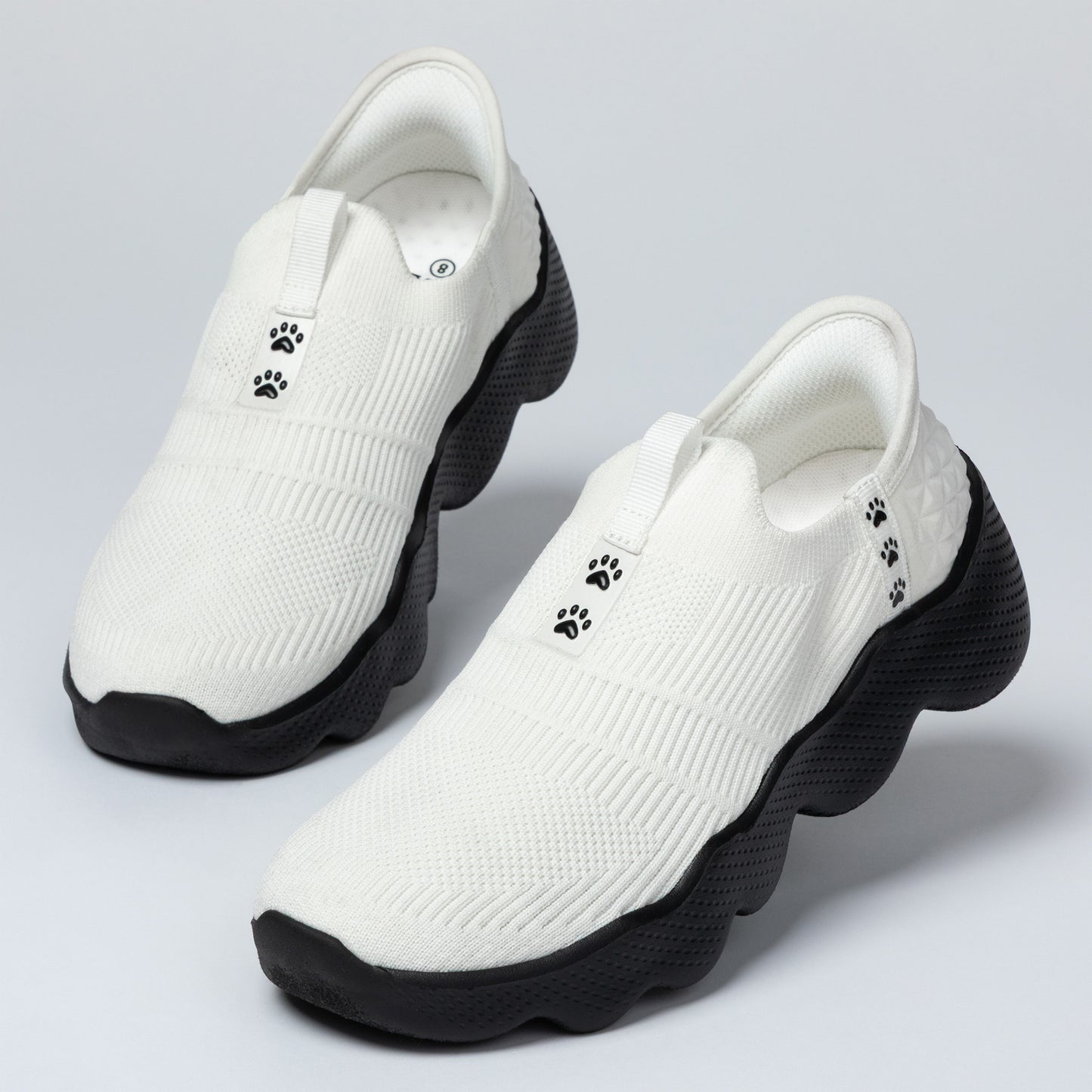 White shoes with black soles and paw prints on a light gray background