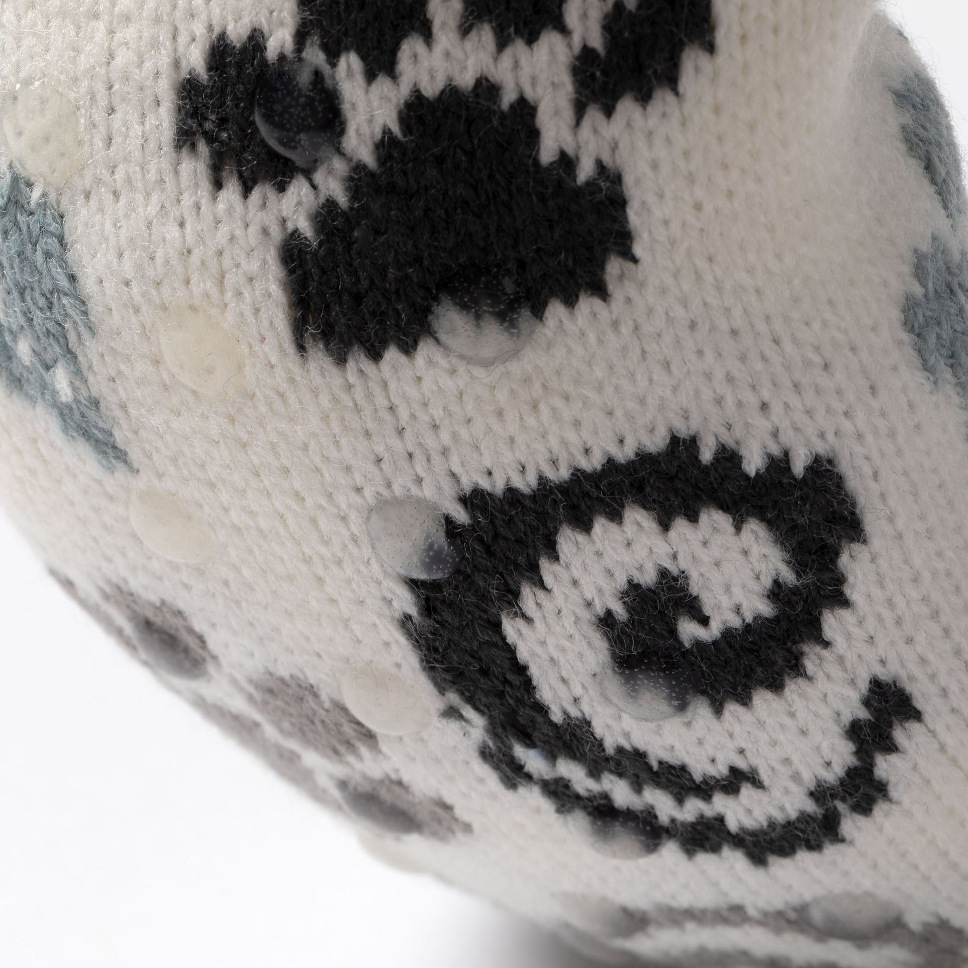 close up of white, blue, gray paw patterned knitted slipper socks, on a carpet floor blue gray paws swirls, showing traction dots