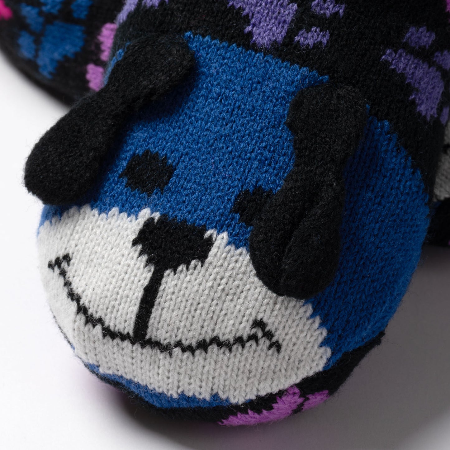 detail shot blue and rainbow paw patterned knitted slipper socks with a smiling dog face on top, on white background rainbow dog