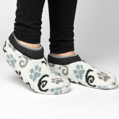 Person wearing white, blue, gray paw patterned knitted slipper socks, on a white background blue gray paws swirls