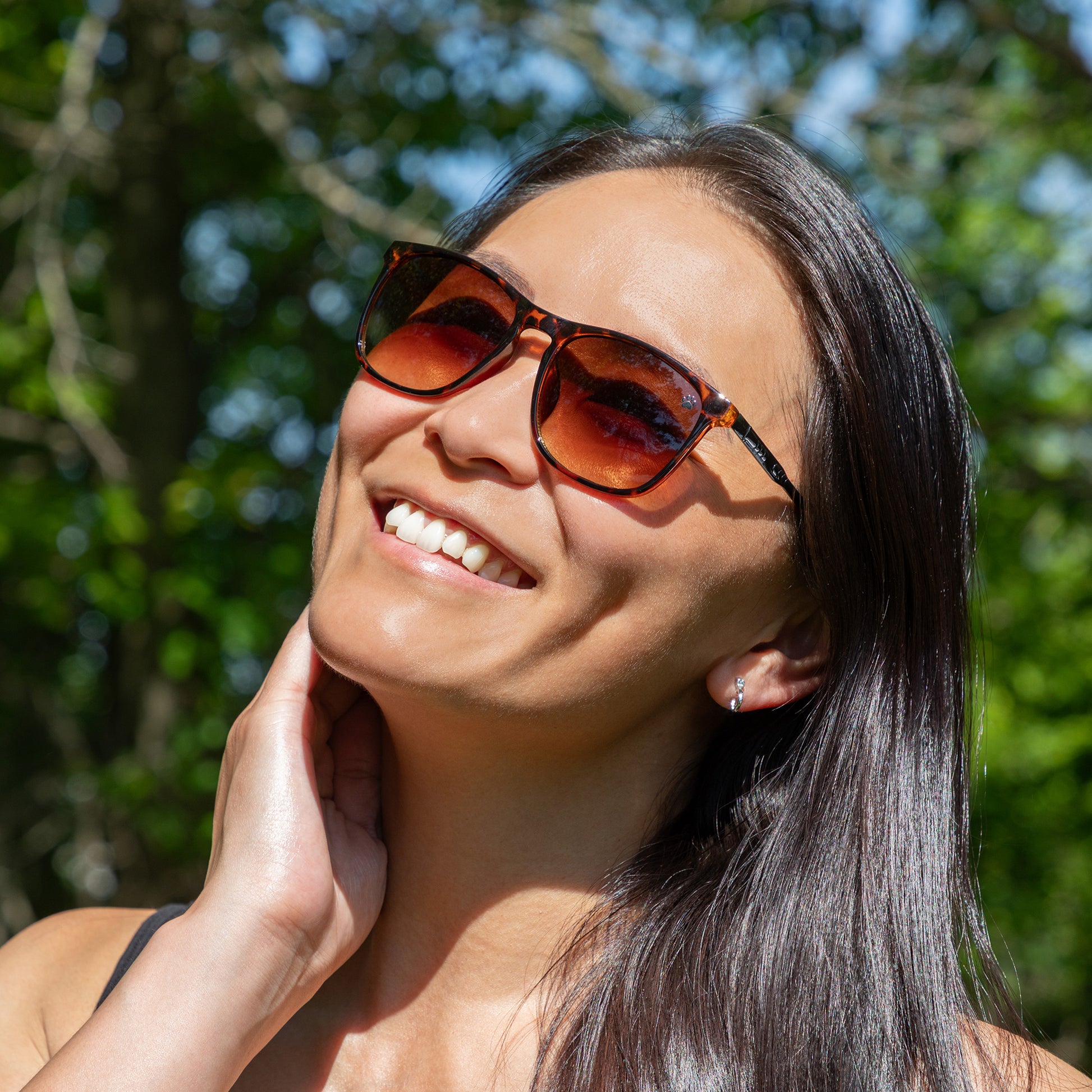 Woman wearing sunglasses with a blurred green outdoor background
