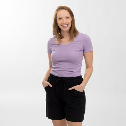 Woman wearing a purple shirt and black shorts on a white background