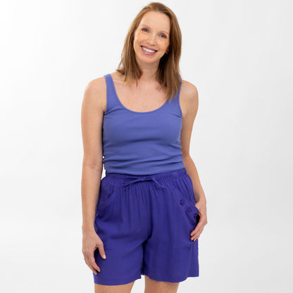 Woman wearing a blue tank top and shorts on a white background