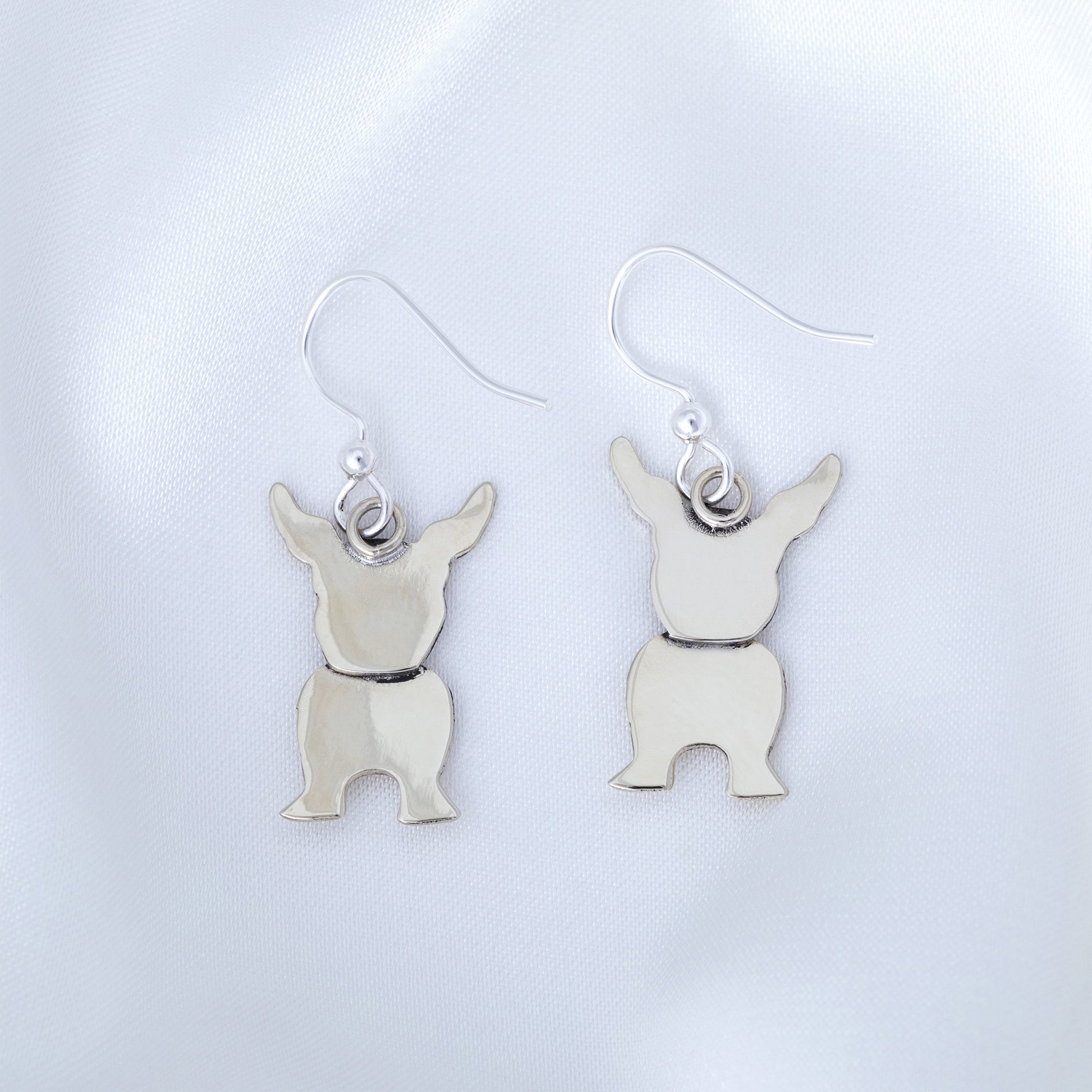 Silver dog-shaped earrings on a light gray background