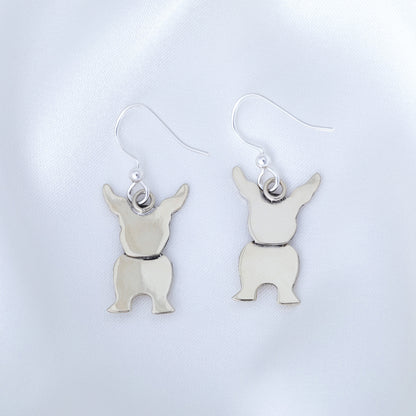 Silver dog-shaped earrings on a light gray background