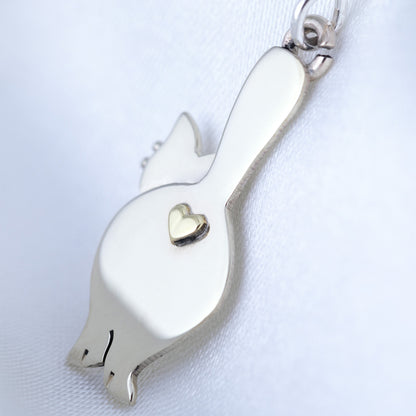 Silver earring shaped like a cat's behind with a heart on a white background