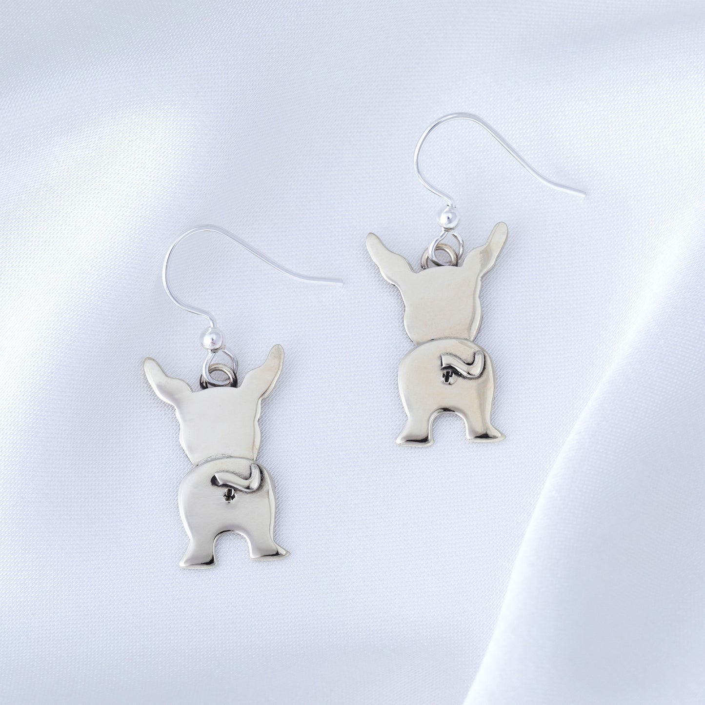 Silver dog-shaped earrings on a light gray background