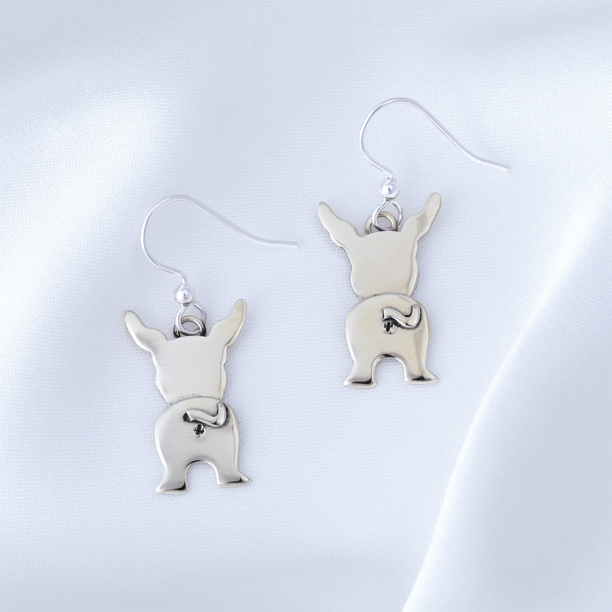 Silver dog-shaped earrings on a light gray background