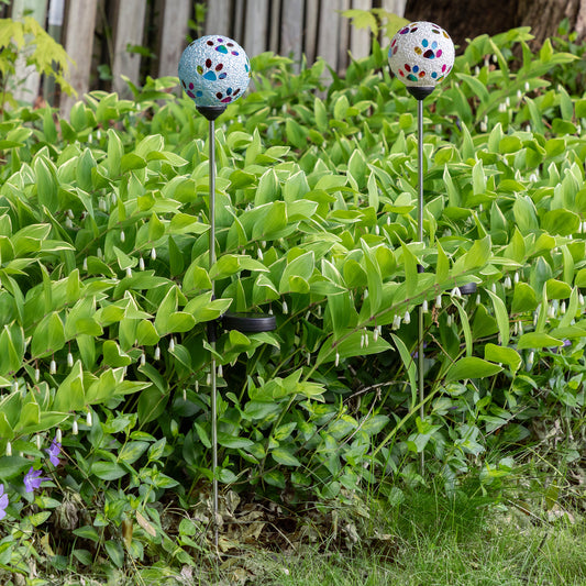 two Multicolor Paws Beaded Solar Garden Stakes, one blue one white, in a garden in the daylight 