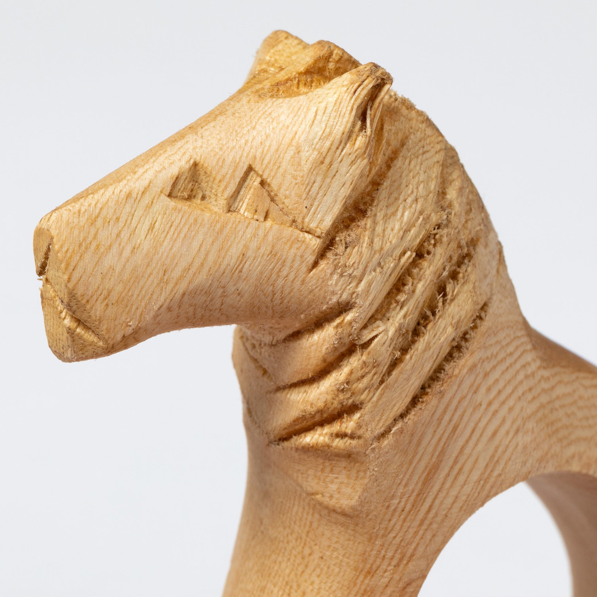 Close up of a wooden carved animal on a napkin ring against a white background.