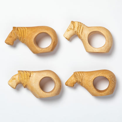 Four wooden napkin rings shaped like animals on a white background
