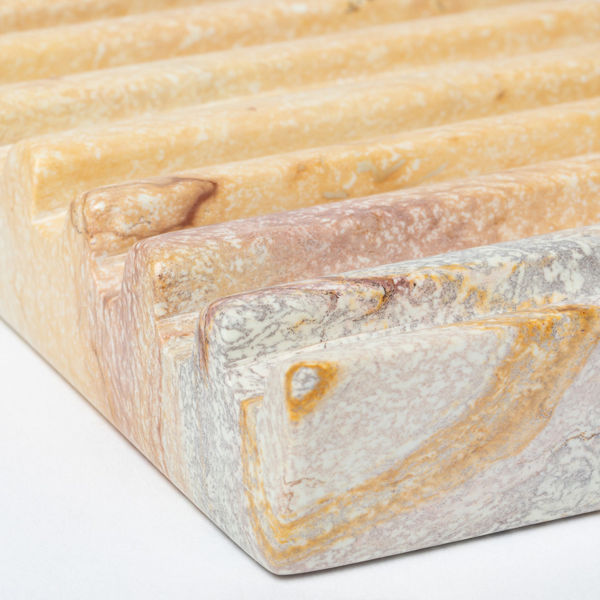 Close-up of a soapstone soap dish with a textured surface on a white background.