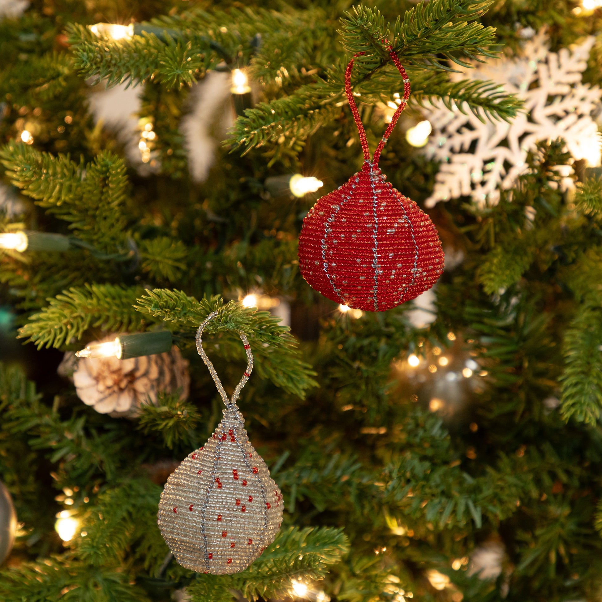 Red and silver beaded Christmas ornaments on a decorated tree.