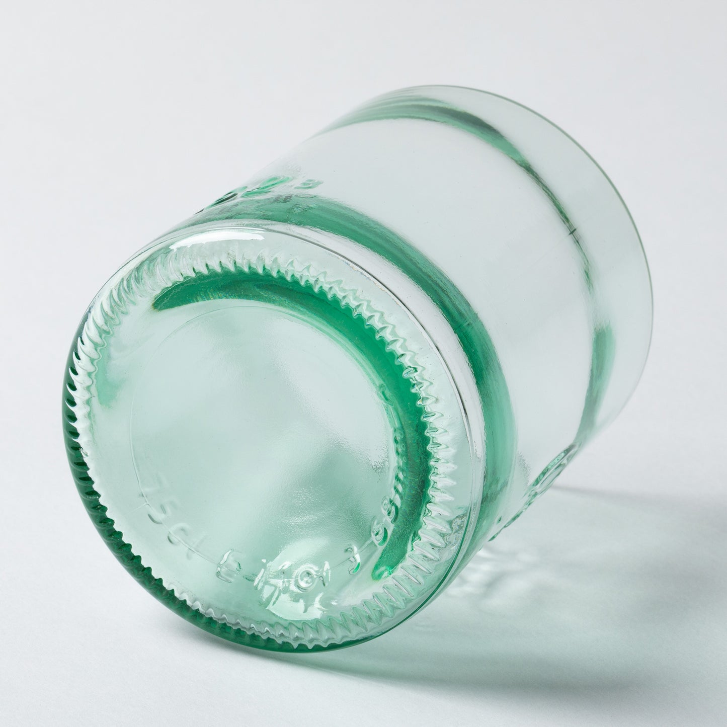 Close-up of a green glass bottle on a light gray background