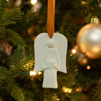 White angel soapstone ornament on a Christmas tree with blurred lights and decorations in the background