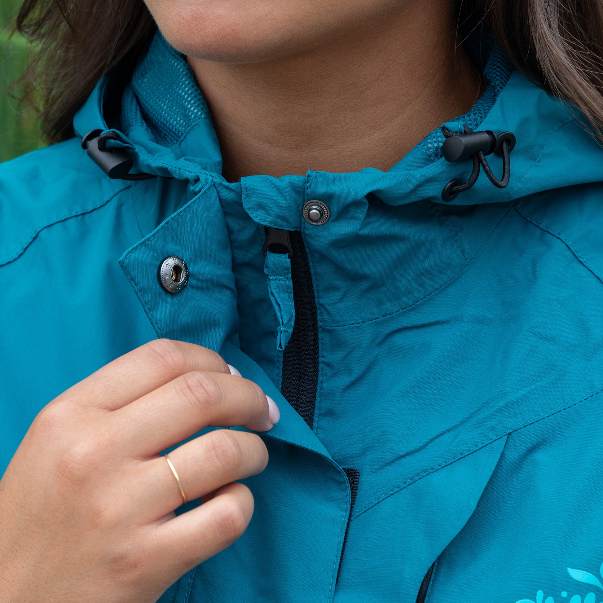 Close-up of a person wearing a blue jacket with a hood, adjusting it.