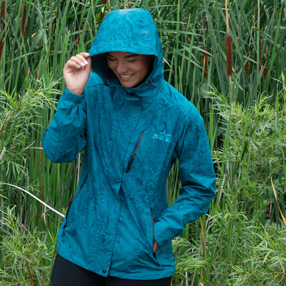 Person wearing a blue raincoat standing in tall green grass.