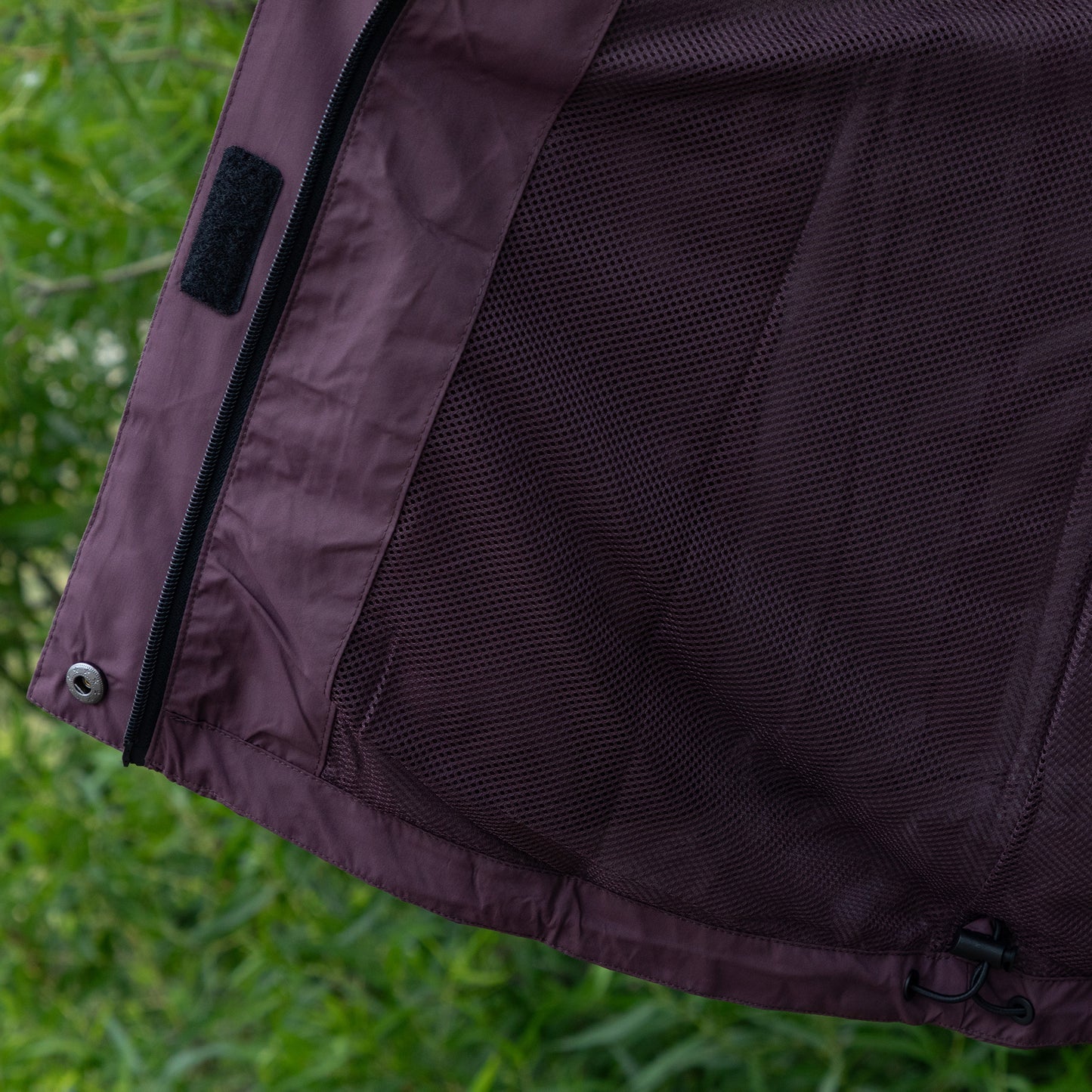 Close-up of a dark purple jacket with mesh lining on a green grass background