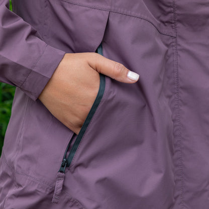 Close-up of a hand zipping up a purple jacket with a blurred green background