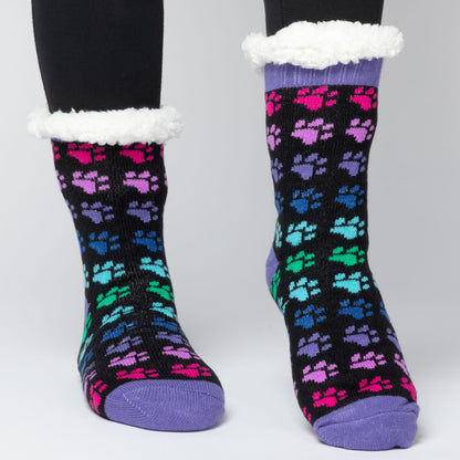 model wearing Pair of rainbow paws Sherpa Fleece Lined Paw Print Cabin Slipper Socks with sherpa trim on a light gray background rainbow paws