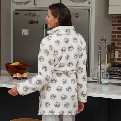 Woman wearing a white short zipper robe with black paw prints in a kitchen.