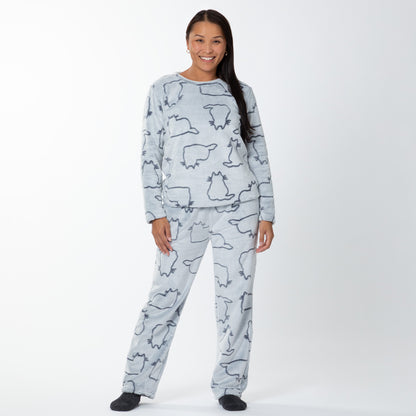 A woman wearing a matching set of fluffy, soft long-sleeve pajamas. The top and pants are light grey and patterned with cute cat outlines. 