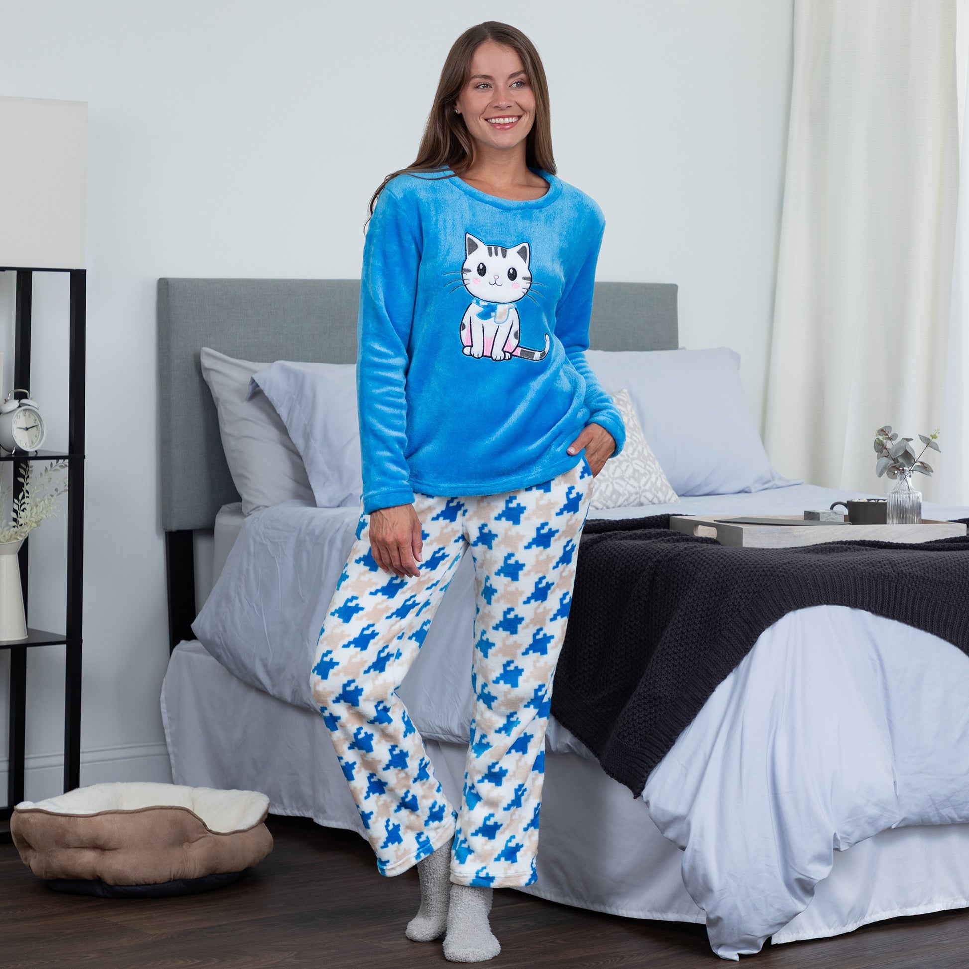 A woman wearing a blue long-sleeve top with an embroidered cute cat design and gray, blue and light blue houndstooth pattern. Design of a blue cat in plush super cozy fabric 