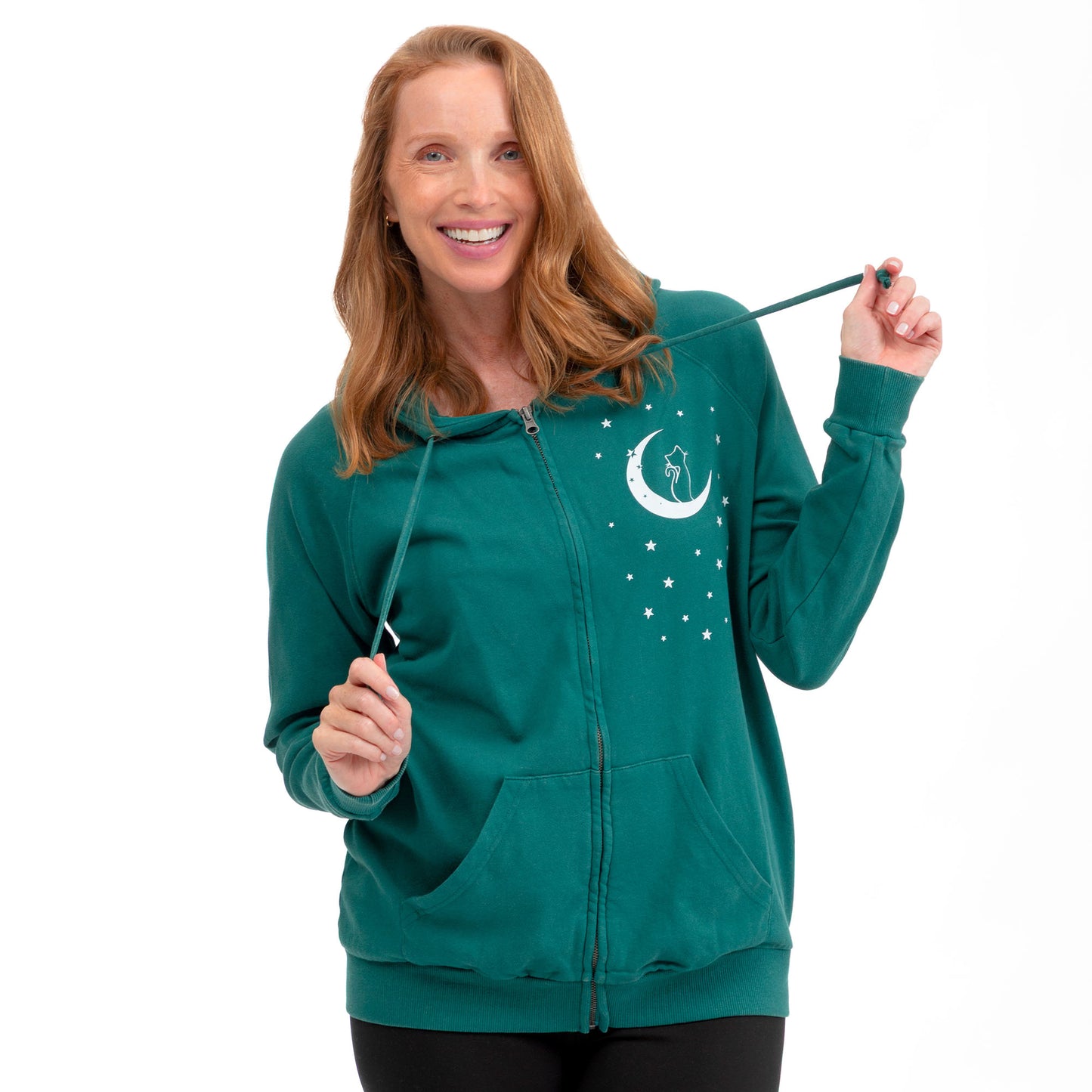 A woman wearing a teal green zip-up hoodie with a white crescent moon and stars graphic on the left chest, holding the drawstrings against a plain white background.